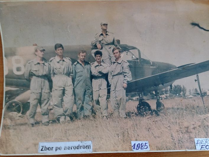 FOTO  Momente memorabile ale istoriei aeronautice vrâncene din timpul pregătirii preliminare pentru zbor a aeronavelor pe aerodromul de la Focșani surprinse în vara anului 1985 cu Avionul Nr. 38- IAR-823. Grupa de zbor a instructorului Lt. Major STRUȚ MARIAN împreună cu tehnicianul avionului M.M1 CERNEI ION (în mijloc) și grupa de zbor(cu autografele celor 5 elevi pe spatele fotografiei).