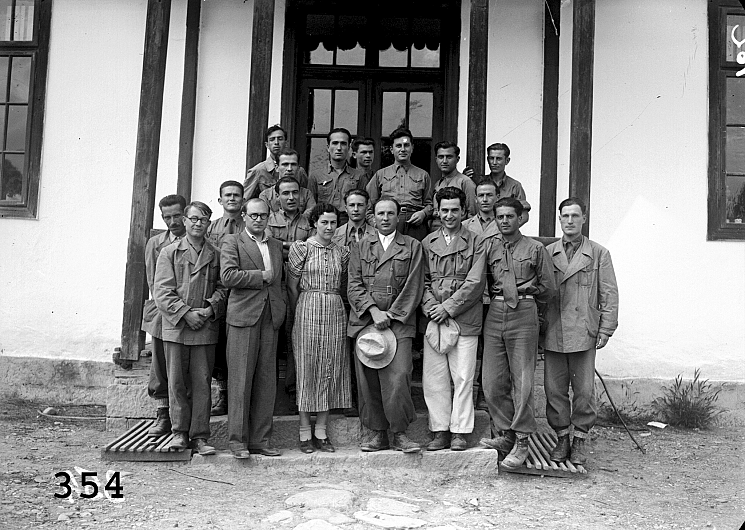 Echipieri, Nereju, Vrancea (1938-1939) Imaginea prezintă echipieri, îmbrăcați în uniformele gri ale Serviciului social, veniți în campanie de cercetare în comuna de munte Nereju, Vrancea. Plecând de la materialele culese de monografiști în 1927, unele dintre ele publicate, în intervalul 15 iulie-15 septembrie 1938 H.H.Stahl și o echipă de opt specialiști (Gh. Serafim, Ion Gh. Filip, C. Brăiloiu, C. Bugeanu. Victor Tufescu, Ion Butură, ing. Petre Stănculescu, dr. D. C. Georgescu, C. Ștefănescu) reiau cercetările la Nereju pentru întocmirea unei monografii. Materialele, completate în prima parte a anului 1938, vor sta la baza lucrării “Nerej, un village d’un région archïéque” care s-a publicat în vederea prezentării la Congresul Internațional de Sociologie de la București din toamna anului 1939. Clișeele au fost conservate în anul 2005 de specialiști ai Arhivei Naționale de Filme a României cu concursul Programului Departamentului de Stat al SUA, prin 