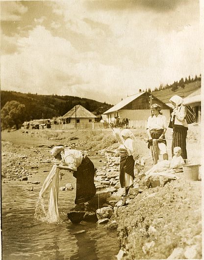La spălat rufe în râul Zăbala- Cercetare monografică Nereju, jud. Vrancea (1927) Imaginea surprinsă de obiectivul aparatului de fotografiat aduce în fața privitorului o secvență din lumea satului: grup de femei la marginea râului care spală rufe. Sunt în port popular de muncă: basma, cămașă simplă, catrință neagră. Un colț al catrinței este ridicat dând astfel posibilitatea de a se mișca mai ușor. În spatele lor se văd acoperișurile unor case, iar pe fundal crestele munților. Cel care a imortalizat toate momentele importante ale acestei campanii monografice, a fost fotograful Iosif Berman (1892-1941), jurnalist și fotograf oficial a Curții Regale.Fotograf: Iosif Berman Instituția de proveniență: Muzeul Național al Satului Dimitrie Gusti - București